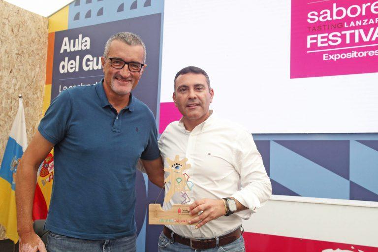 Oswaldo Betancort y Marci Acuña muestran en el recinto de Saborea Lanzzarote un detalle con la figura de la mascota de DIVER