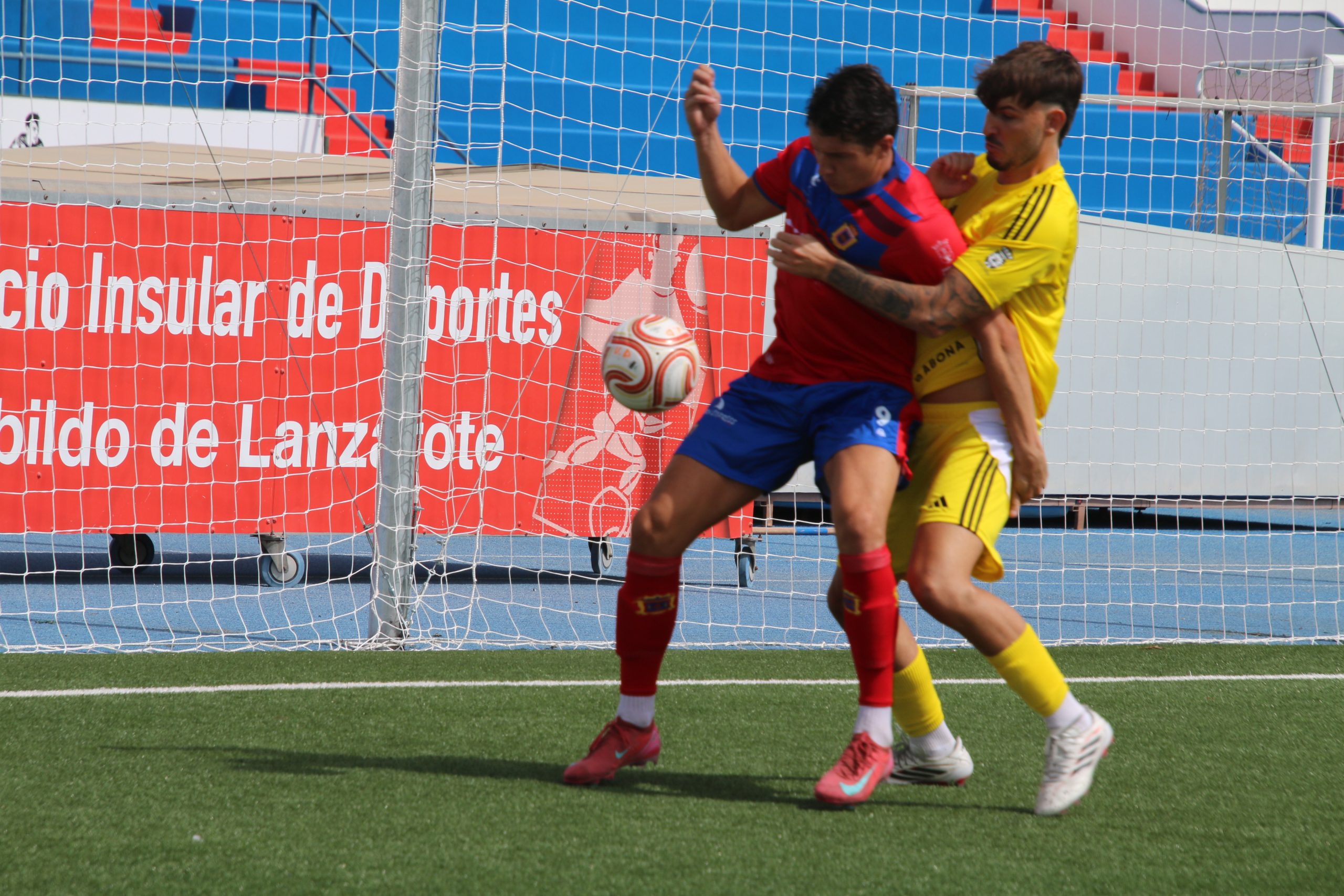 Un jugador de la UD Lanzarote disputa el balón con un futbolista del CD San Miguel junto a la portería