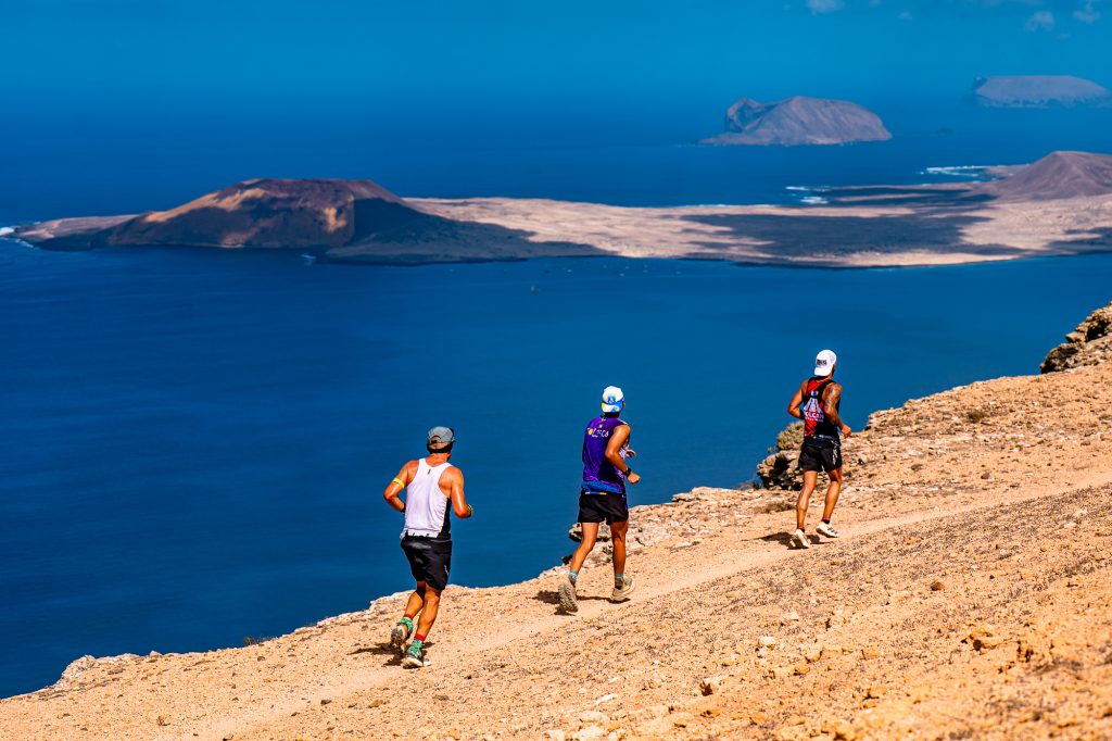 Corredores de Unique Trail Lanzarote en un sendero con vistas a La Graciosa