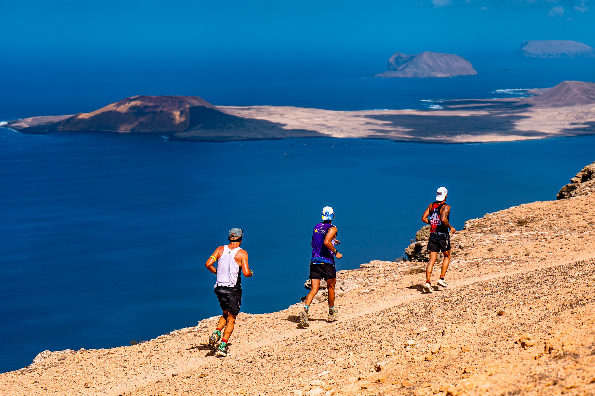 Corredores de Unique Trail Lanzarote en un sendero con vistas a La Graciosa
